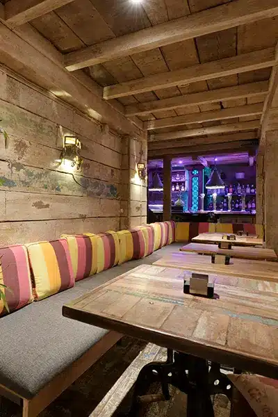 dining-room-restaurant-with-sofa-along-wall-row-colored-cushions-with-wooden-tables